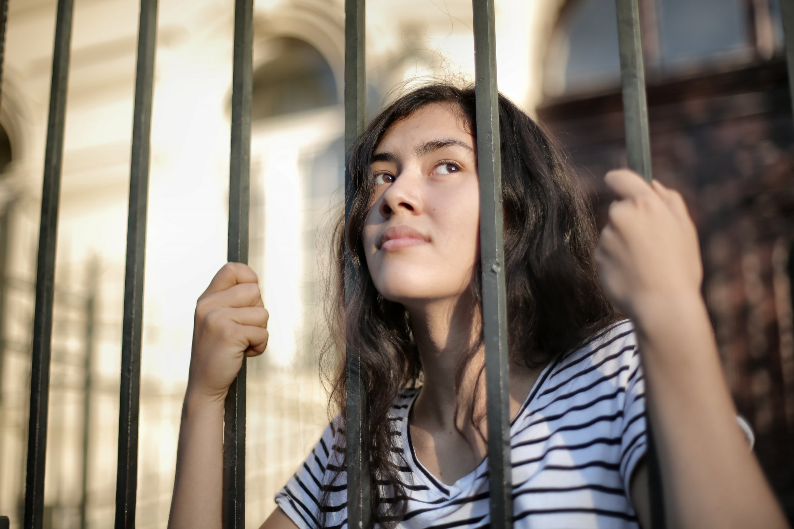 A young woman looks out thoughtfully through railings. Is she seeing an opportunity in crisis